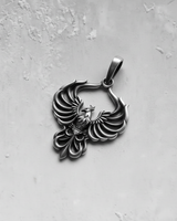 Close-up of stylized phoenix necklace charm showing detailed metalwork and bail loop for chain attachment