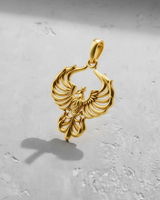 Close-up of a silver phoenix pendant under bright studio lighting, showcasing the bird's detailed crest and form.