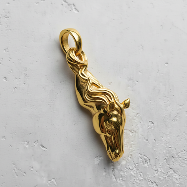 14K gold vermeil silver horse pendant with a flowing mane design, shown from a top-down angle on a light textured background.