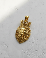 14K gold vermeil crowned lion pendant showing detailed mane and regal crown, angled on a light grey textured surface.