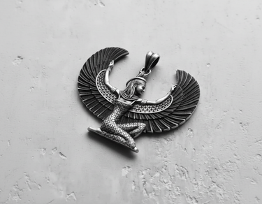 High angle shot of handcrafted silver winged Isis pendant displaying detailed headdress and patterned dress design