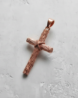 Rose gold rustic cross pendant with a warm metallic finish, showing the intricate rope knot and rough-hewn details of the design.