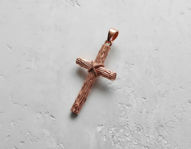 Rose gold plated silver rustic cross pendant with detailed wood grain texture on white background