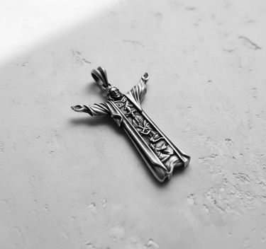 Angled top-down view of the handcrafted silver Jesus Christ pendant, highlighting the oxidized finish and outstretched arms.