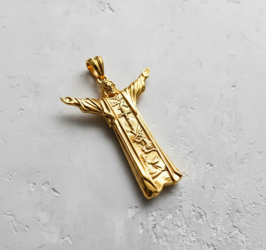 Front view of gold vermeil Jesus Christ pendant with outstretched arms and detailed religious robe carvings on white