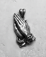 Angled side view of the silver praying hands pendant, showcasing the three-dimensional craftsmanship of the clasped hands and cuffs.