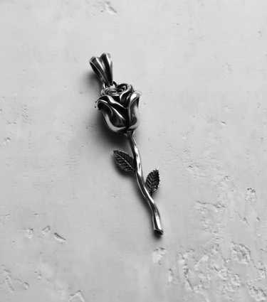 Angled shot of the handcrafted silver rose pendant, highlighting the oxidized finish and intricate details on the petals.