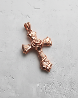 Silver rose cross pendant with a polished rose gold plating, showing the central rose and vine details on a light grey surface.
