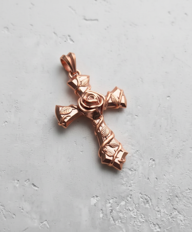 Silver rose cross pendant with a polished rose gold plating, showing the central rose and vine details on a light grey surface.
