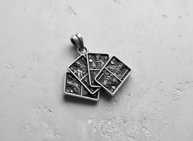 Silver Four Kings Pendant with four detailed playing cards fanned out, shown on a textured light gray surface.