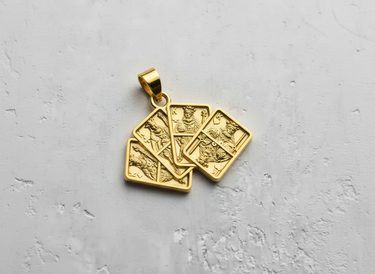 14K gold vermeil playing card pendant showcasing four fanned-out king cards against a light grey textured surface.