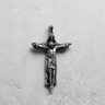 Silver crucifix pendant showing the full design of God the Father holding the crucified Jesus, on a textured white background.