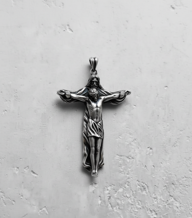 Silver crucifix pendant showing the full design of God the Father holding the crucified Jesus, on a textured white background.