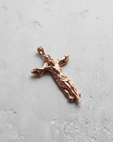 Rose gold plated Crucifixion pendant showing a stylized figure of Jesus forming the cross on a light gray background.