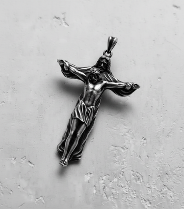 Angled view of the sterling silver crucifix pendant, highlighting the 3D sculpting and oxidized details of the figures.