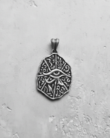 Flat lay close-up of handcrafted silver Eye of Horus pendant featuring intricate hieroglyphs and vintage finish