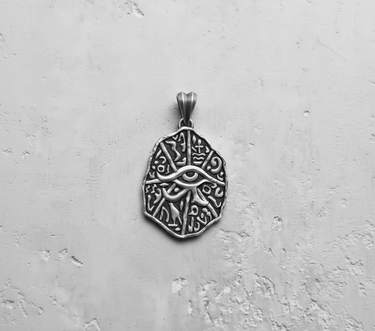 Close-up of silver Egyptian Eye pendant showing detailed relief carving of the Eye of Horus and ancient symbols