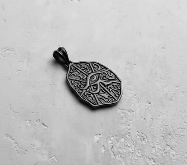 Side angle shot of the Silver Eye of Horus Pendant, revealing its thickness and the polished bail on a light gray background.