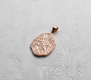 Rose gold plated Eye of Horus pendant with hieroglyphic texture on grey background