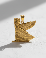 Gold vermeil silver Isis goddess pendant with detailed wings, photographed on a white textured background with shadow.