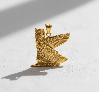 Gold vermeil silver Isis goddess pendant with detailed wings, photographed on a white textured background with shadow.