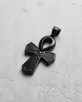 Black rhodium plated silver Ankh pendant with a detailed Eye of Horus and radiating lines, on a textured light gray surface.