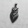 925 sterling silver owl pendant with an oxidized finish highlighting the intricate feather and face details on a concrete background.