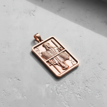 Rose gold-plated Silver Jack Pendant displayed on a concrete surface, with light casting a shadow to emphasize its depth.