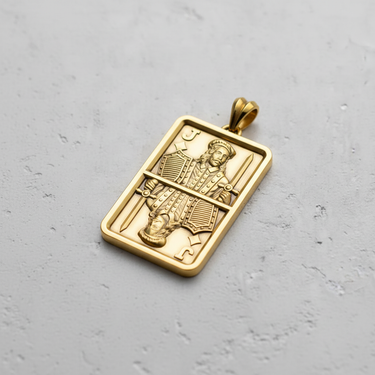 Gold vermeil silver Jack pendant with a mirrored playing card design, shown at an angle on a textured grey surface.