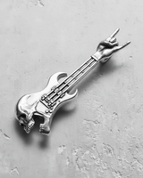Polished silver skull guitar pendant with a rock hand gesture headstock, shown from a top-down angle on a gray surface.