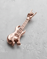 Rose gold vermeil rock guitar pendant showcasing the intricate skull face and guitar details on a textured concrete-style surface.