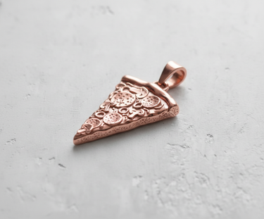 Rose gold plated version of the Silver Pizza Pendant showing detailed pepperoni toppings on a light gray concrete surface.