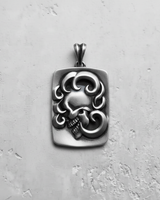Oxidized 925 sterling silver skull pendant, highlighting the deep shadows and intricate details of the profile and swirls.