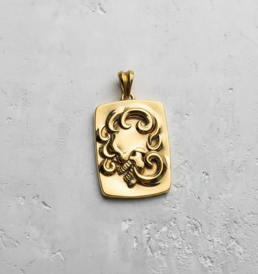 Gold-plated ornate skull pendant in a rectangular shape, highlighting the polished finish and baroque-style details.