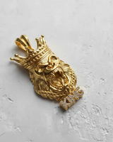14K gold vermeil silver gorilla pendant with a detailed crown and iced-out KING lettering, shown on a white textured surface.