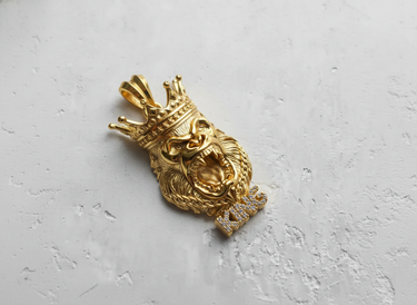 14K gold vermeil silver gorilla pendant with a detailed crown and iced-out KING lettering, shown on a white textured surface.