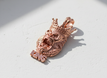 Rose gold plated Silver King Gorilla Pendant with pink iced-out 'KING' lettering and intricate crown details on a white surface.