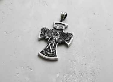 Angled shot of handcrafted silver archangel pendant showing intricate wing and sword relief