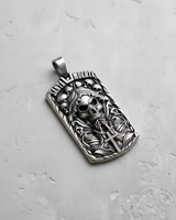 Angled view of silver Santa Muerte pendant showing hooded skull and praying hands relief