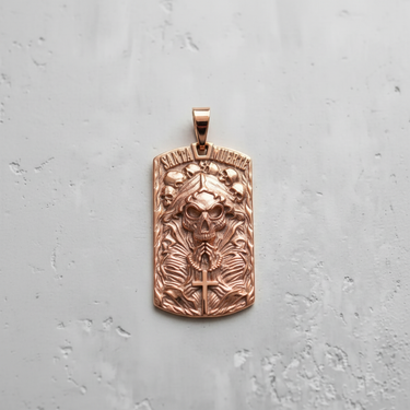 Rose gold plated silver Santa Muerte pendant in dog tag shape with praying hands and skull details on grey background