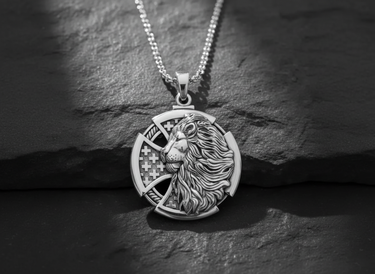 Silver lion cross pendant with chain, showing the detailed lion head and interwoven cross design on a dark slate background.