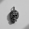 Silver skull snake pendant with an oxidized finish in a dramatic black and white photo showing deep shadows and detail.