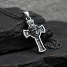 Oxidized sterling silver Jesus cross pendant showing detailed scrollwork and a matching silver chain on black slate rock.