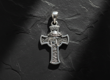 Silver Jesus Cross Pendant featuring the face of Christ with a crown of thorns and INRI inscription on a dark slate background.