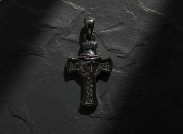 Top-down view of the Silver Jesus Cross Pendant with INRI scroll, showing dramatic lighting on a dark stone background.