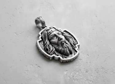 Angled view of the oxidized silver Jesus pendant, showcasing the intricate details of the hair, beard, and ornate bail.