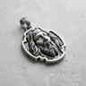 Silver Jesus Christ pendant with an oxidized finish, showcasing the detailed facial features and ornate frame on a grey surface.