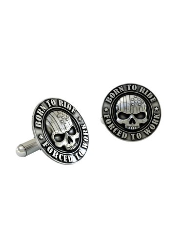 An extreme close-up of a Born to Ride Cufflink, emphasizing the fine details of the flag engraving on the skull and the bold lettering.