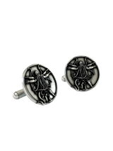 An extreme close-up of a sterling silver Cthulhu Cufflink, emphasizing the fine details of the tentacles, wings, and humanoid form.