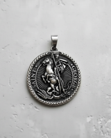 Silver Saint George pendant with detailed high relief of the knight and dragon on a textured light grey surface.